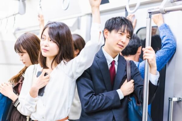 通勤ラッシュの電車内にいる社会人の男女